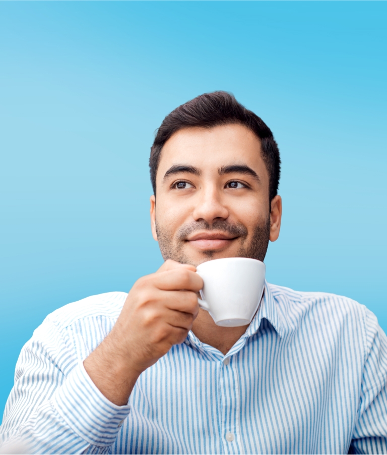 man sitting at desk holding mug